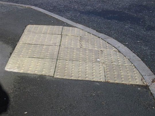 A tactile dropped kerb which contrasts with its surround surfaces
